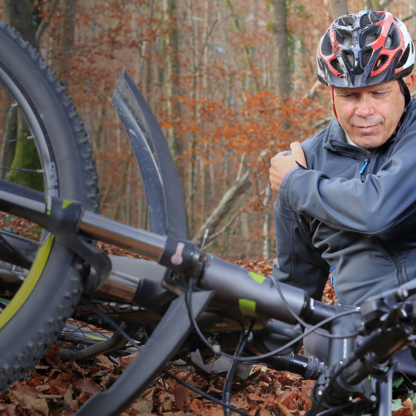 Lifestylebild Mann mit Fahrrad im Wald gestürzt, Schulterschmerz