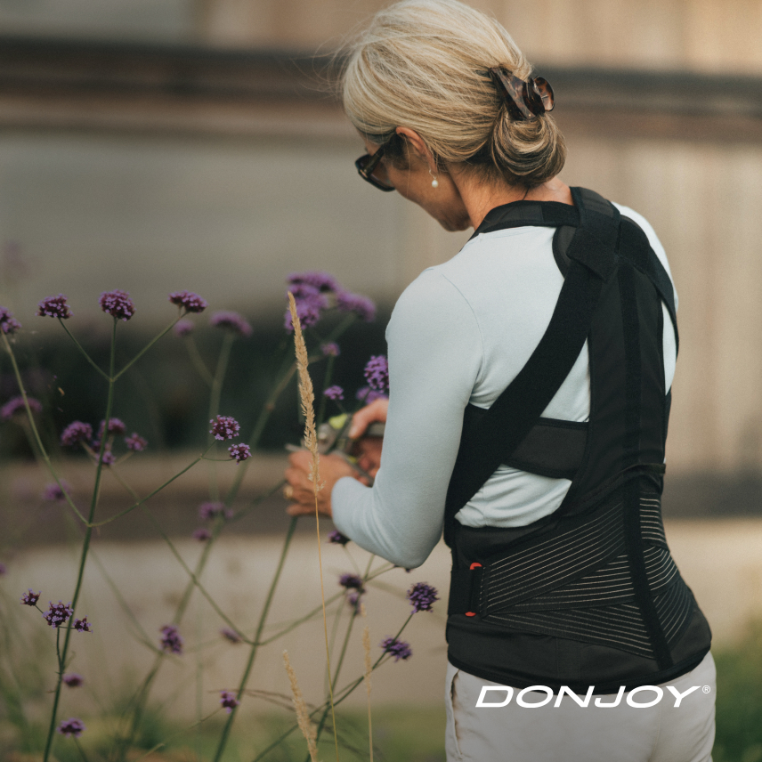Imagebild DONJOY® OsteoStrap Frau im Garten, Rückenorthese zur aktiven Entlastung der LWS/BWS